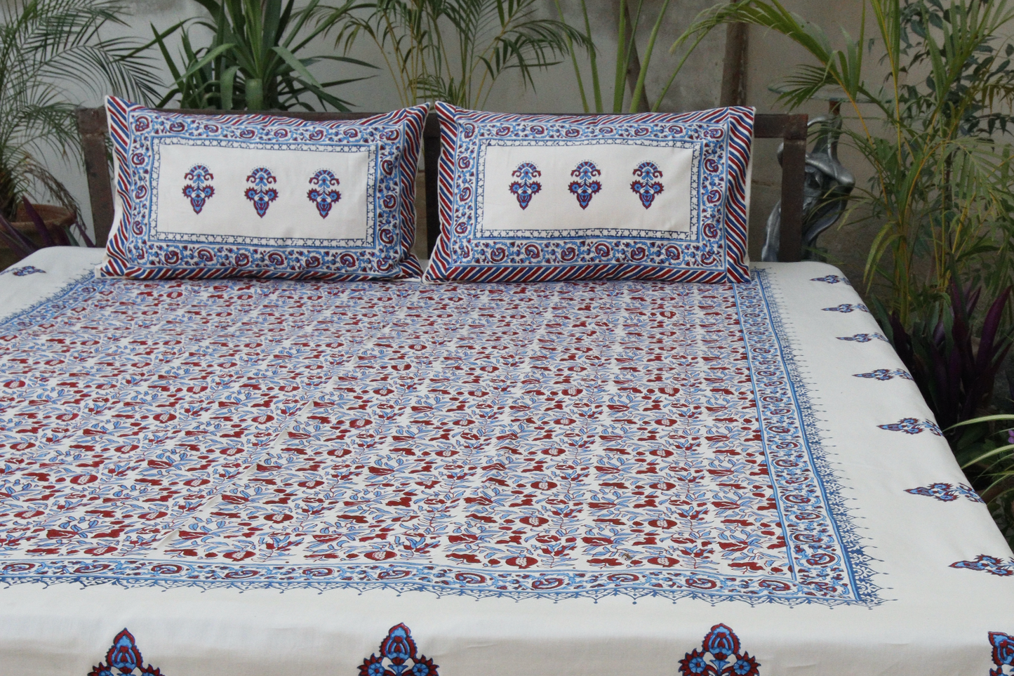 hand block printed bedspread with intricate patterns on a bed outdoors.